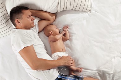 Father and baby sleeping on bed together, top view. Space for text