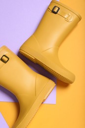 Photo of Pair of yellow rubber boots on color background, top view