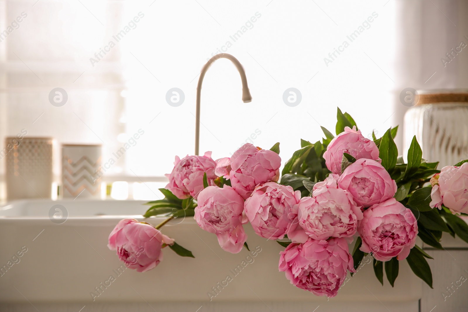 Photo of Bouquet of beautiful pink peonies in kitchen sink