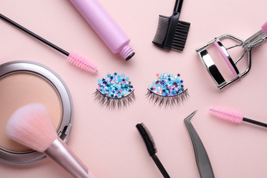 Photo of Flat lay composition with false eyelashes and cosmetic accessories on pink background