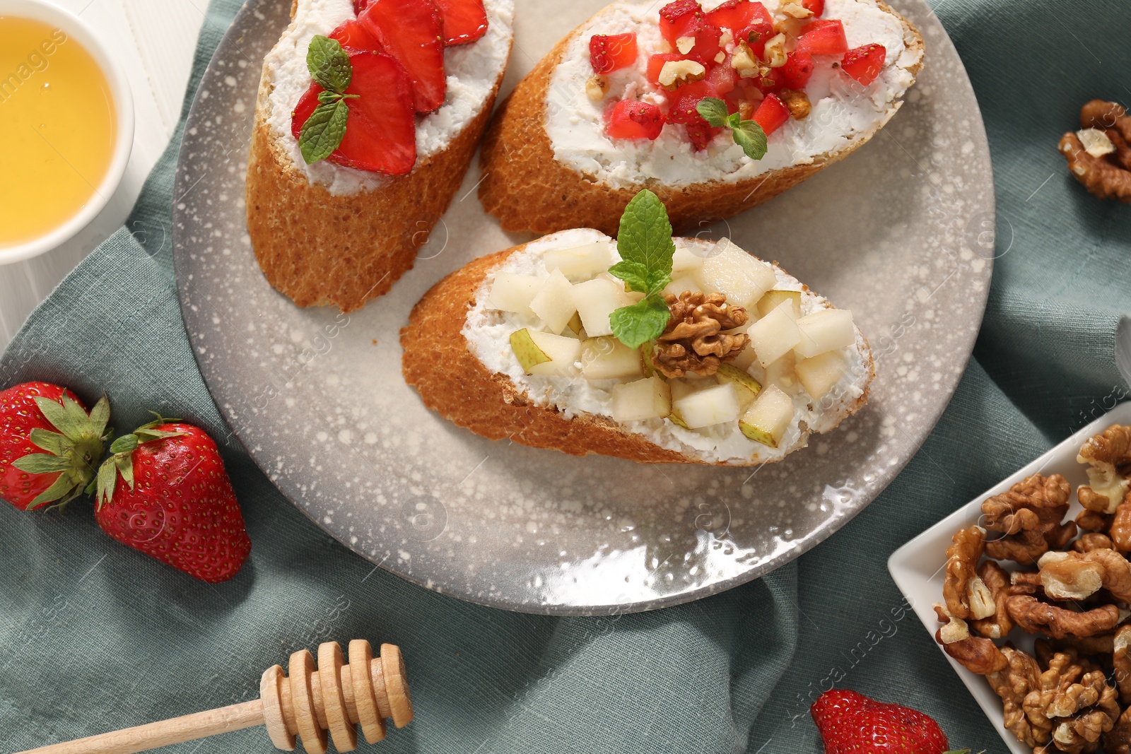 Photo of Delicious ricotta bruschettas with pear, strawberry and walnut on table, flat lay