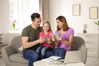 Happy family counting money on sofa at home