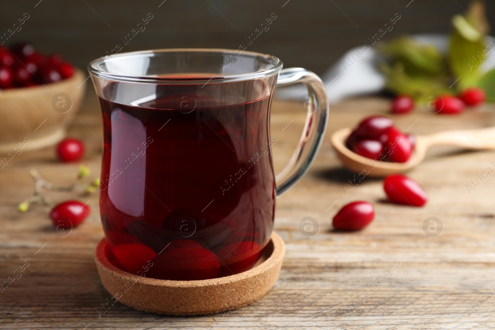 Photo of Glass cup of fresh dogwood tea with berries on wooden table. Space for text