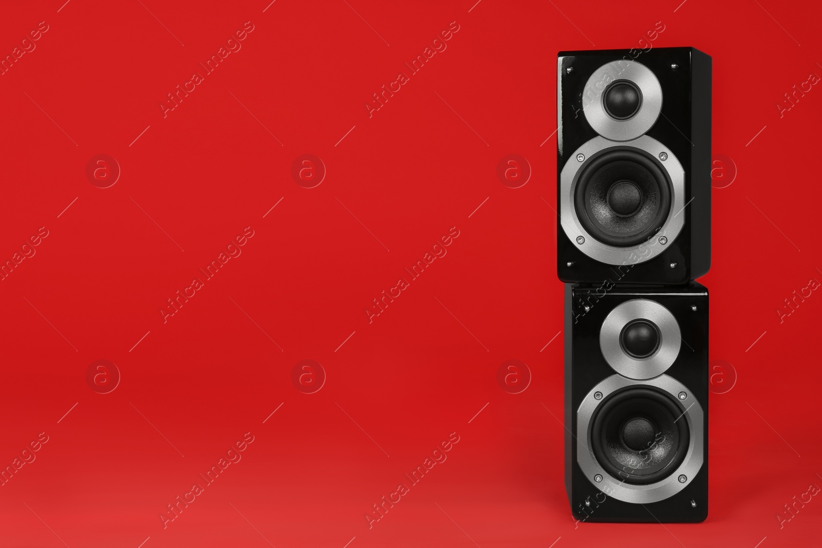 Photo of Modern powerful audio speakers on red background, space for text