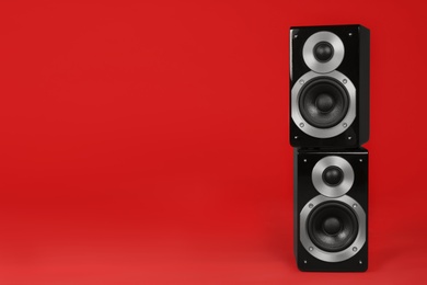 Modern powerful audio speakers on red background, space for text