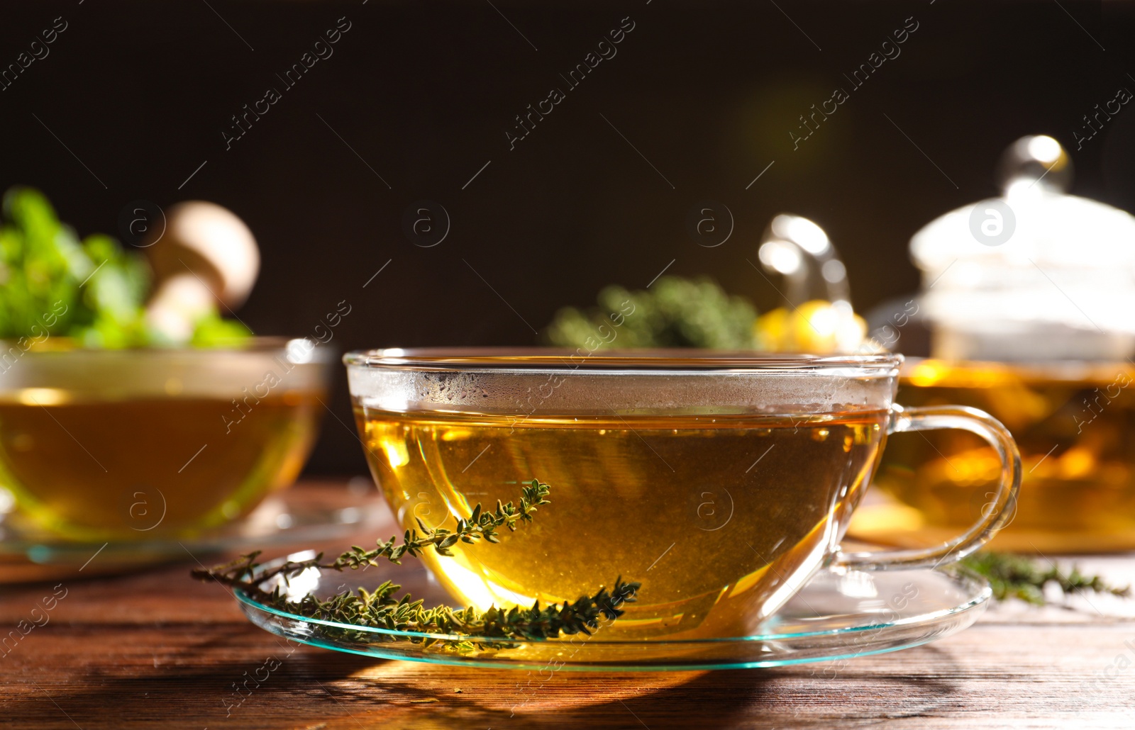 Photo of Cup of aromatic herbal tea and fresh thyme on wooden table