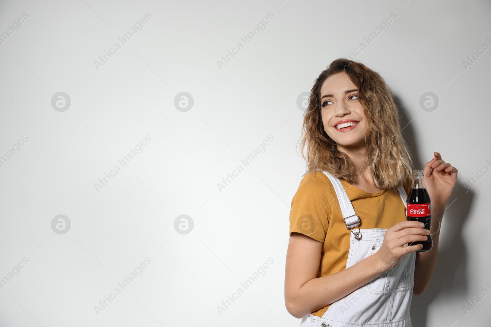 Photo of MYKOLAIV, UKRAINE - NOVEMBER 28, 2018: Young woman with bottle of Coca-Cola on white background. Space for text