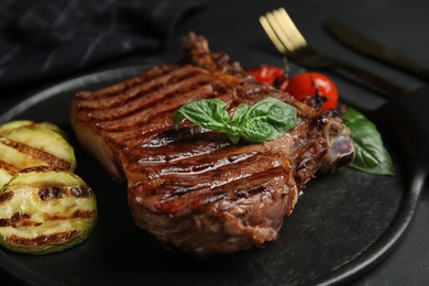Photo of Board with grilled meat steak on black table, closeup