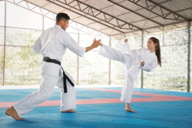 Photo of Girl practicing karate with coach on tatami outdoors