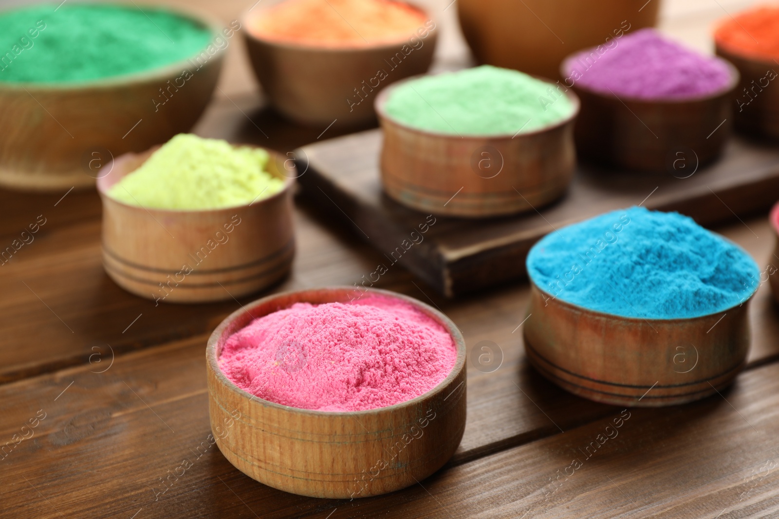 Photo of Colorful powder dyes on wooden background, closeup. Holi festival