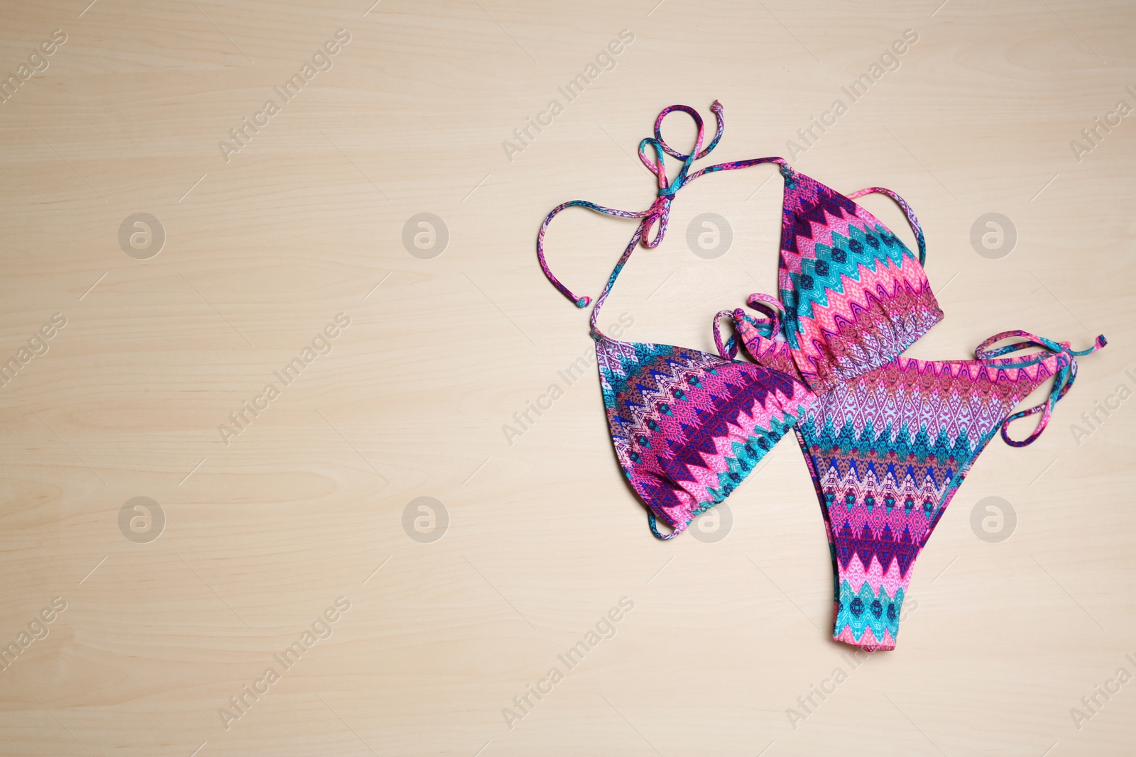 Photo of Stylish bikini and space for text on wooden background, flat lay