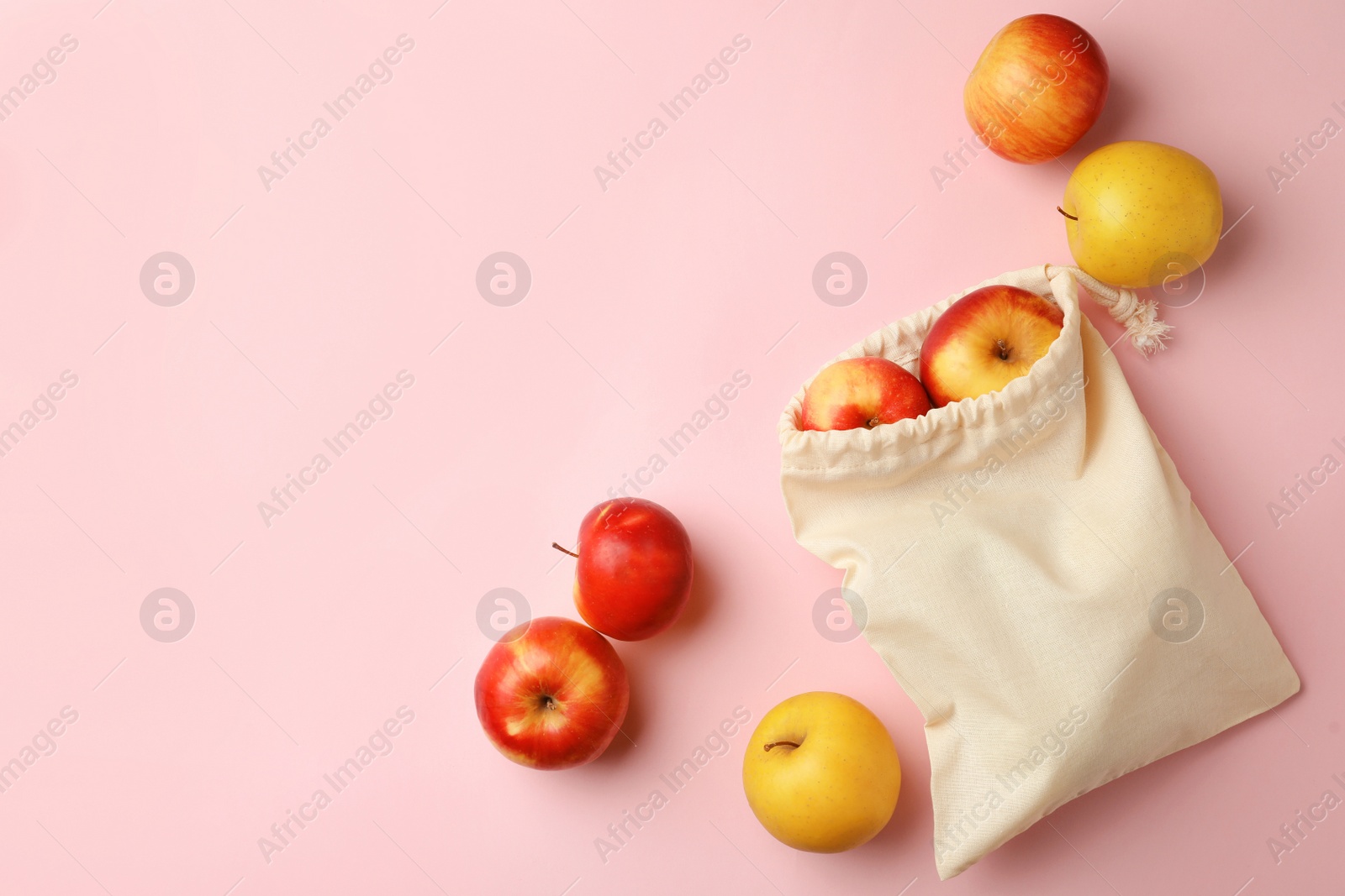 Photo of Cotton eco bag and apples on pink background, flat lay. Space for text