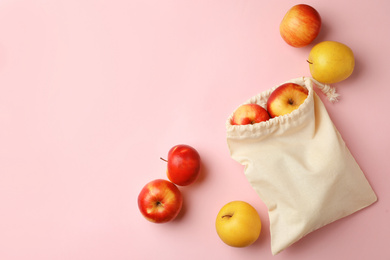 Cotton eco bag and apples on pink background, flat lay. Space for text