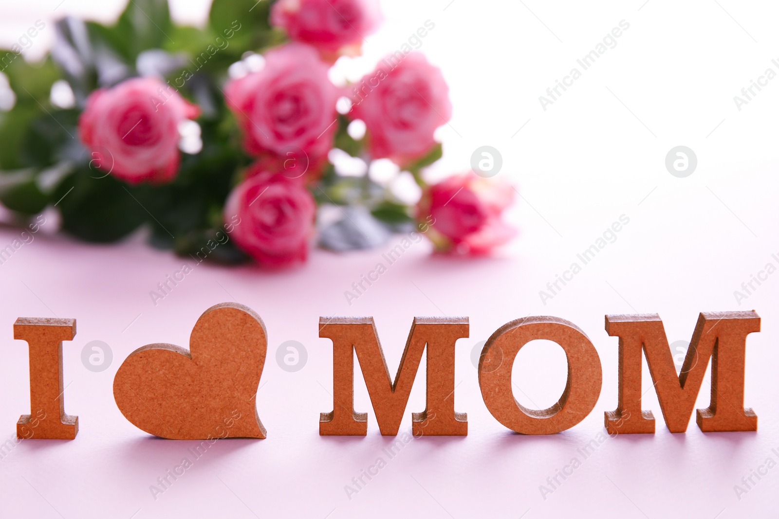 Photo of Phrase "I LOVE MOM" made of letters and flowers on background. Happy Mother's Day