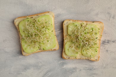 Photo of Tasty sandwiches with cucumber and microgreens on textured table, top view