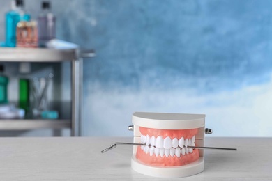 Photo of Typodont teeth and dentist mirror on table. Space for text