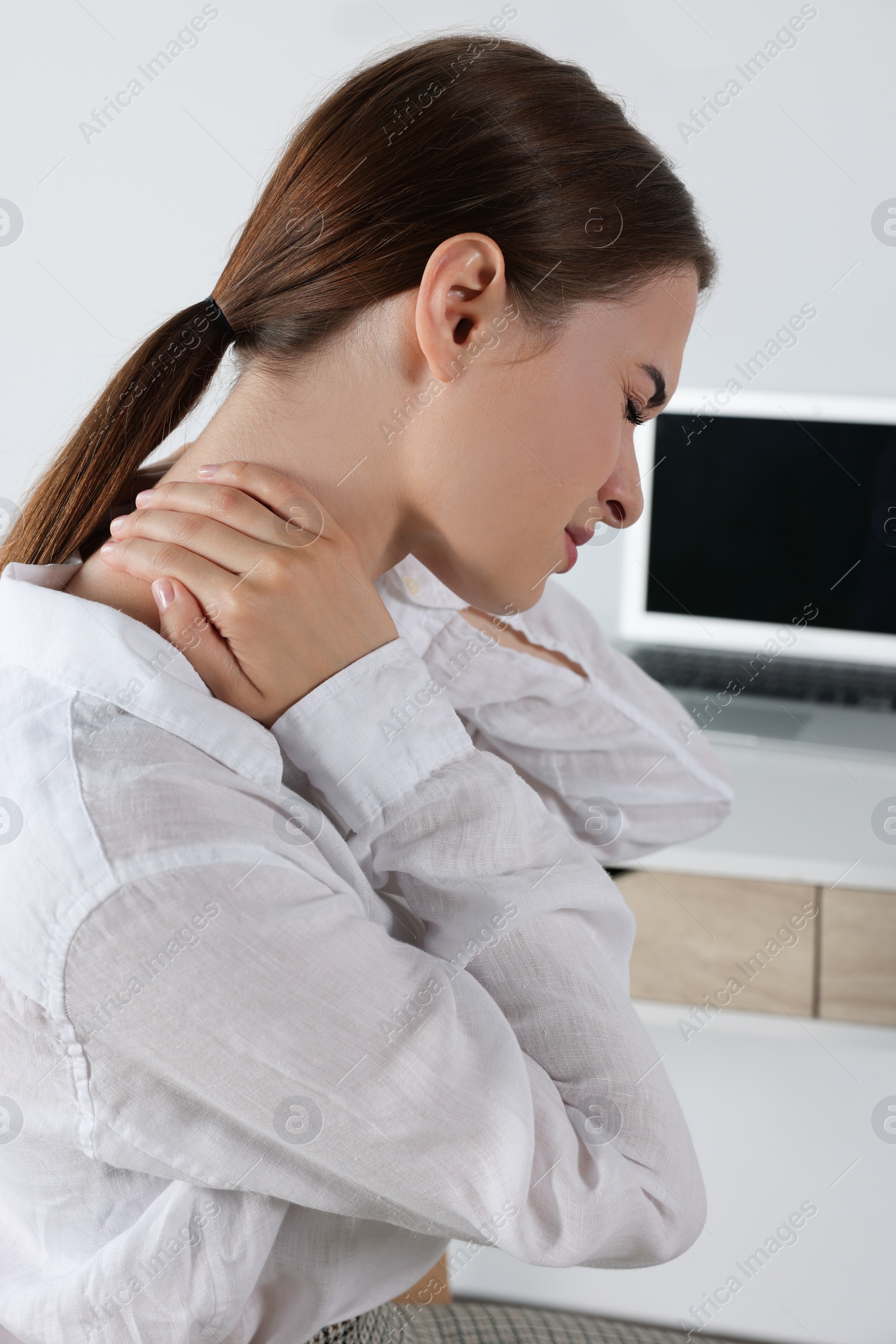 Photo of Woman suffering from neck pain in office