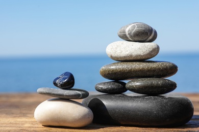 Photo of Stacks of stones on wooden pier near sea, space for text. Zen concept