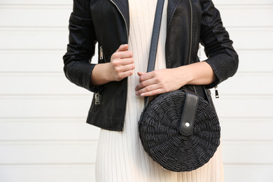 Young woman with stylish handbag near white wall, closeup