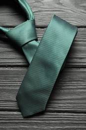 Photo of One green necktie on black wooden table, top view