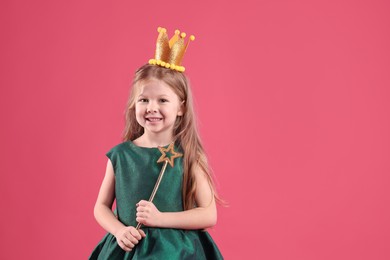 Photo of Cute girl in fairy dress with golden crown and magic wand on pink background, space for text. Little princess