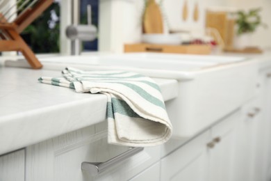 Photo of Clean towel on white table in kitchen, closeup view