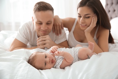 Happy couple with their newborn baby on bed