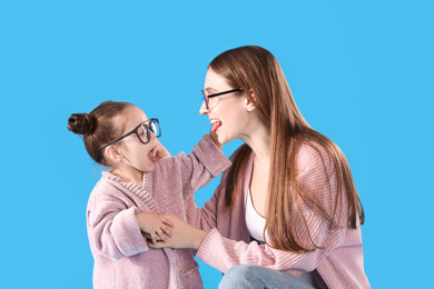 Photo of Young mother and little daughter with glasses on blue background