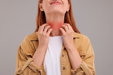 Photo of Suffering from allergy. Young woman scratching her neck on grey background, closeup