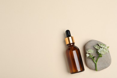 Photo of Bottle with cosmetic oil, stone and flower on beige background, flat lay. Space for text