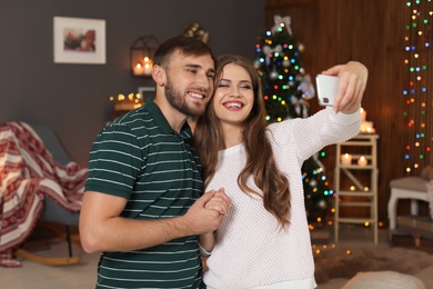 Photo of Happy young couple taking selfie in decorated for Christmas room