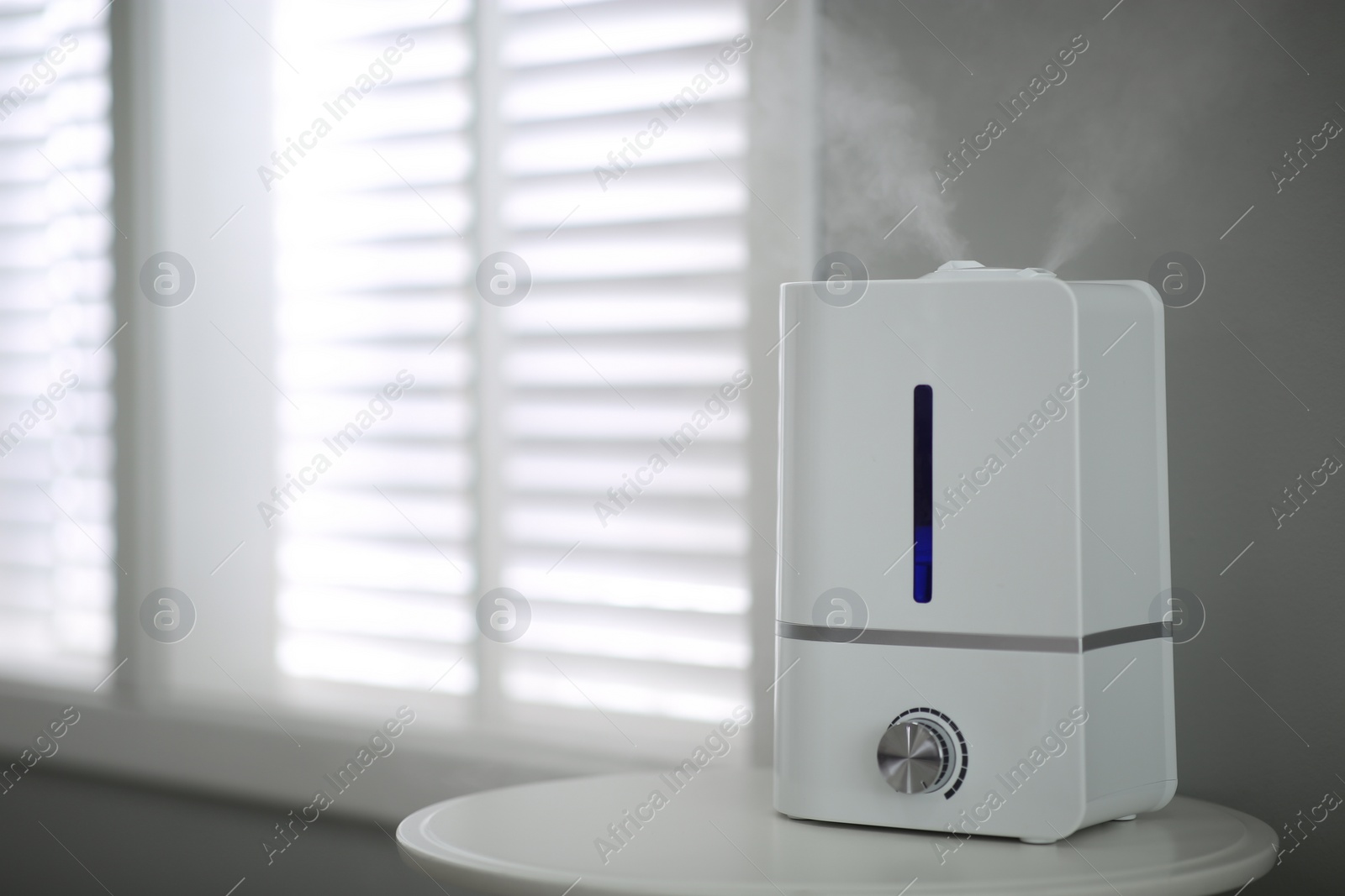 Photo of Modern air humidifier on table indoors. Space for text