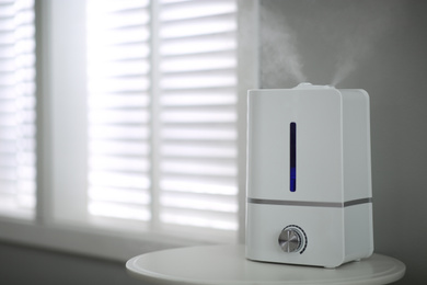 Photo of Modern air humidifier on table indoors. Space for text