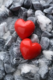 Red decorative hearts on stones and water, top view