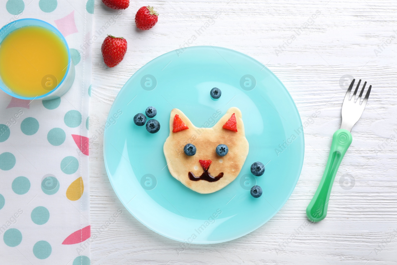 Photo of Tasty pancake served with berries and juice on white wooden table, flat lay. Creative idea for kids breakfast