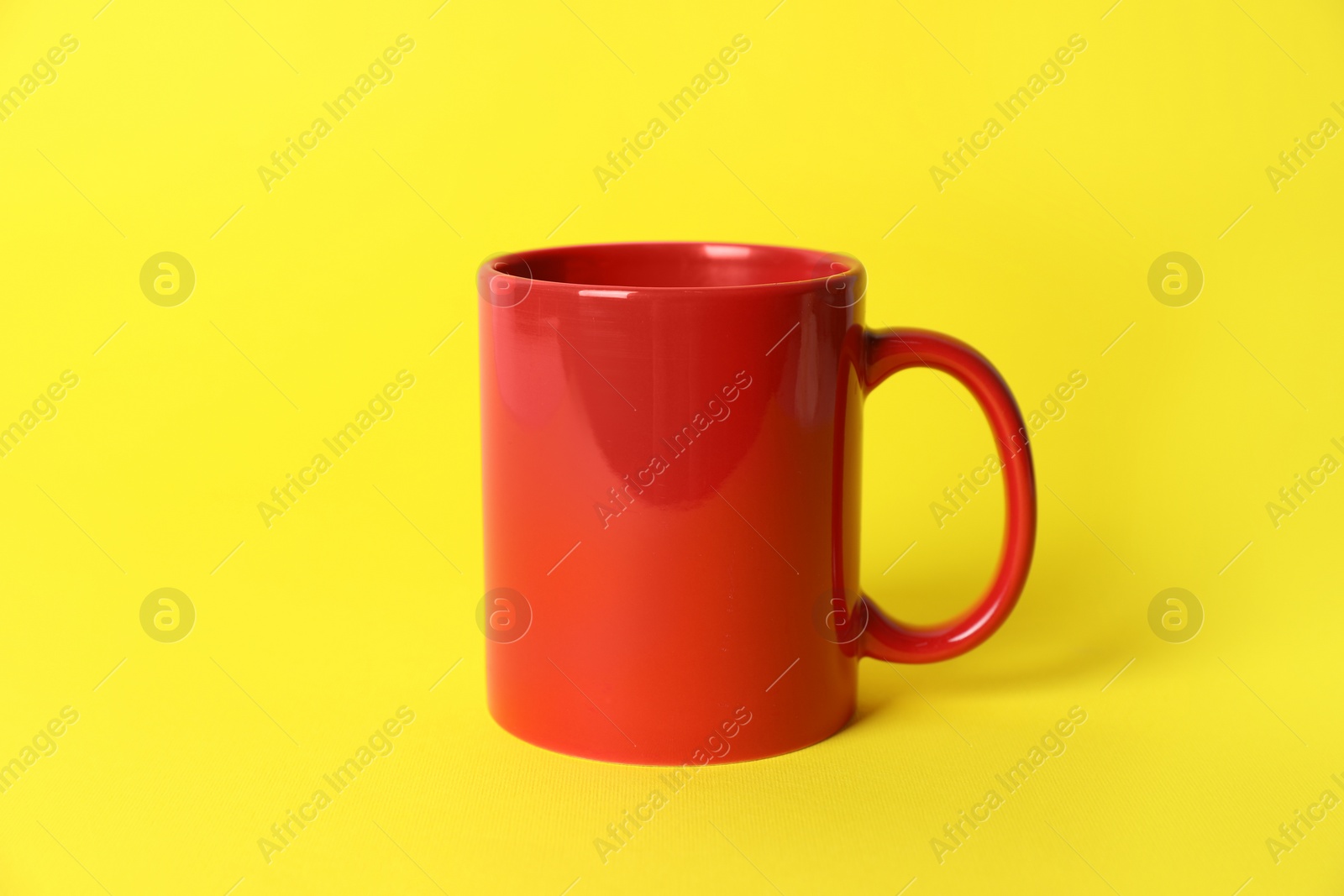 One red ceramic mug on yellow background Photo of One red ceramic mug on yellow background