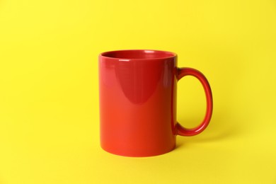 Photo of One red ceramic mug on yellow background