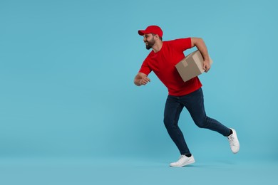 Photo of Happy young courier running to deliver parcel on light blue background, space for text