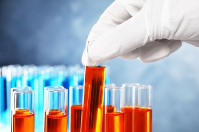 Photo of Scientist taking test tube with liquid sample on grey background, closeup