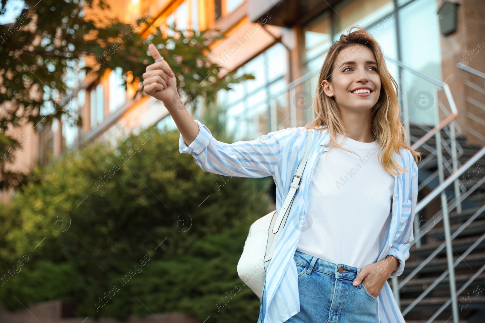 Photo of Young woman hitchhiking taxi on city street