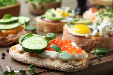 Different delicious sandwiches with microgreens on wooden board, closeup