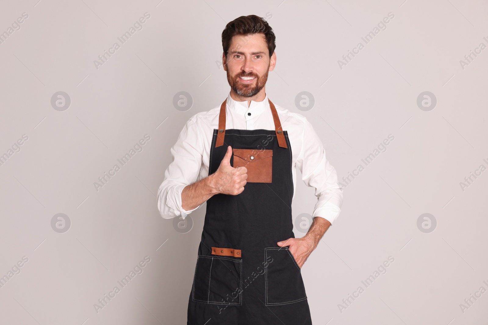 Photo of Smiling hairdresser showing thumb up on light grey background