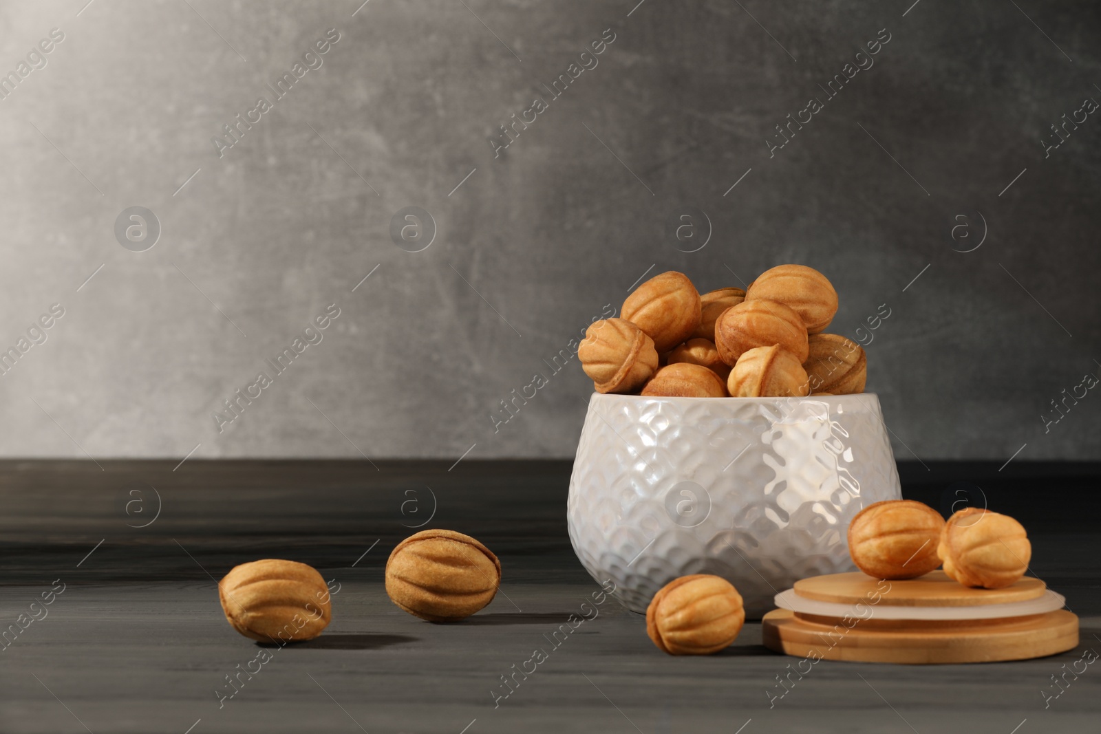 Photo of Freshly baked walnut shaped cookies on grey wooden table, space for text. Homemade pastry filled with caramelized condensed milk