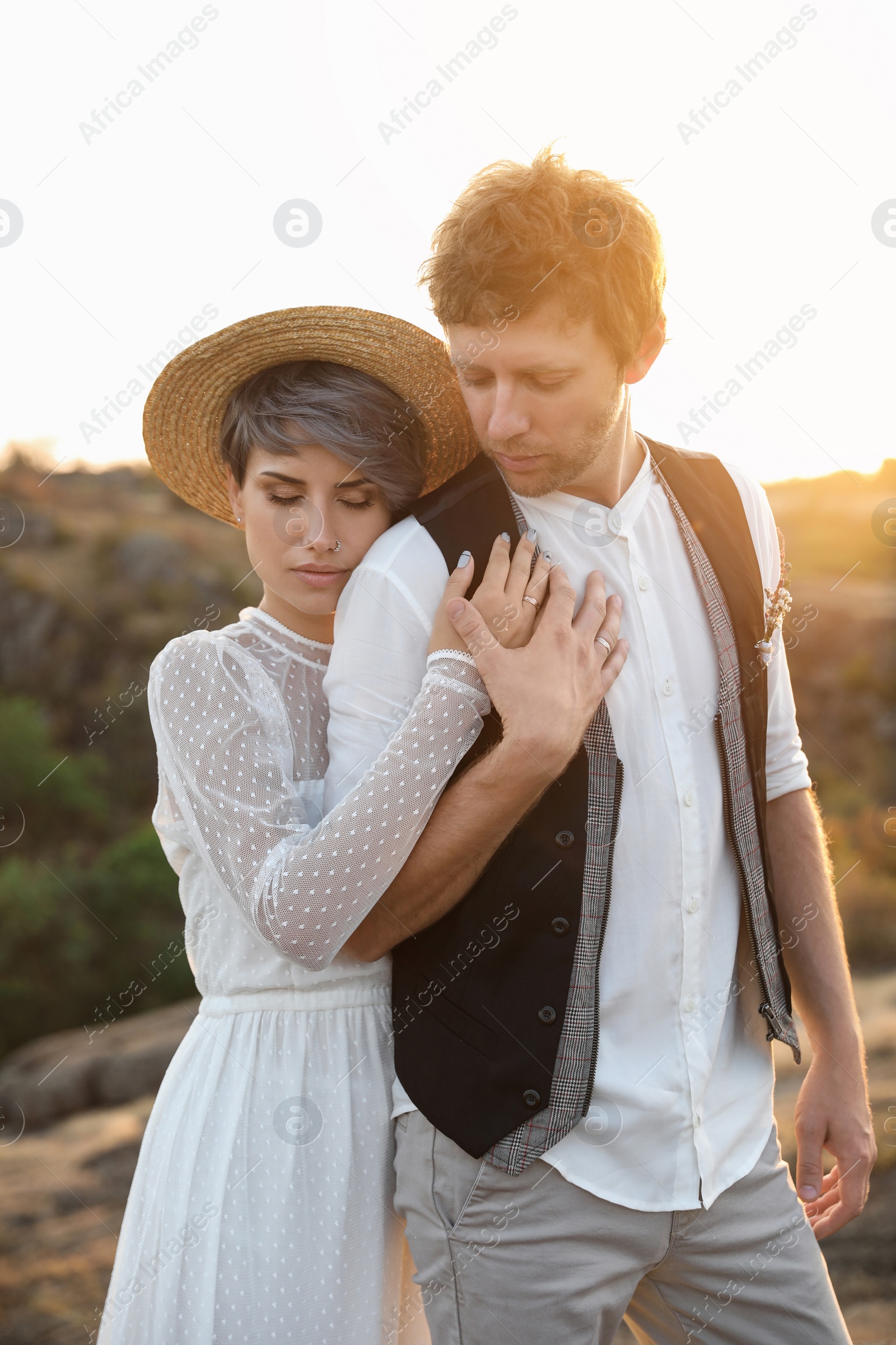 Photo of Happy bride and groom standing outdoors at sunset