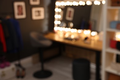Photo of Blurred view of makeup room with stylish mirror on dressing table, chair and clothes rack
