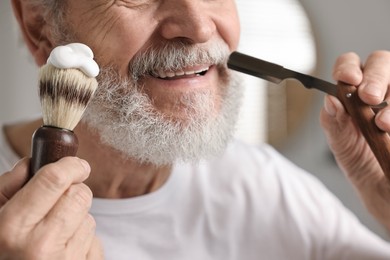 Photo of Man shaving mustache with blade in bathroom, closeup