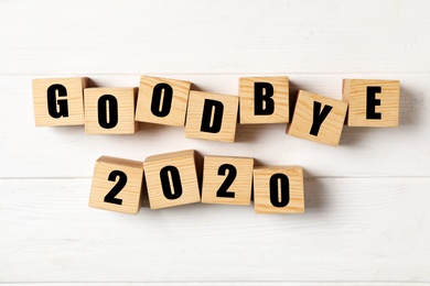 Photo of Cubes with phrase Goodbye 2020 on white wooden table, flat lay