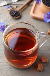 Photo of Glass cup of tea and cornflowers on wooden table, closeup