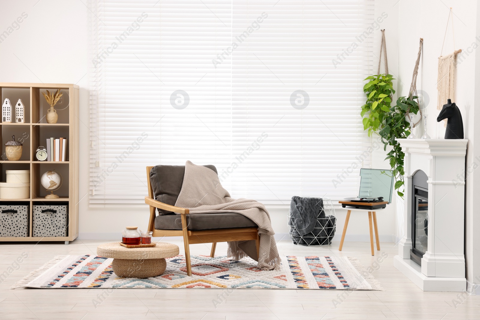 Photo of Stylish living room interior with comfortable armchair, blanket and fireplace