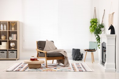 Photo of Stylish living room interior with comfortable armchair, blanket and fireplace